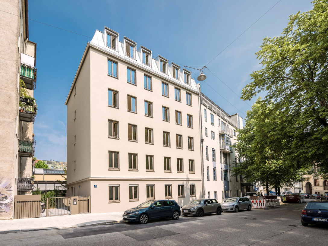 Fassadenansicht des Wohnhauses an der Stollbergstraße. Davor stehen einige geparkte Autos, links vom Haus ist der Eingang in den Innenhof.