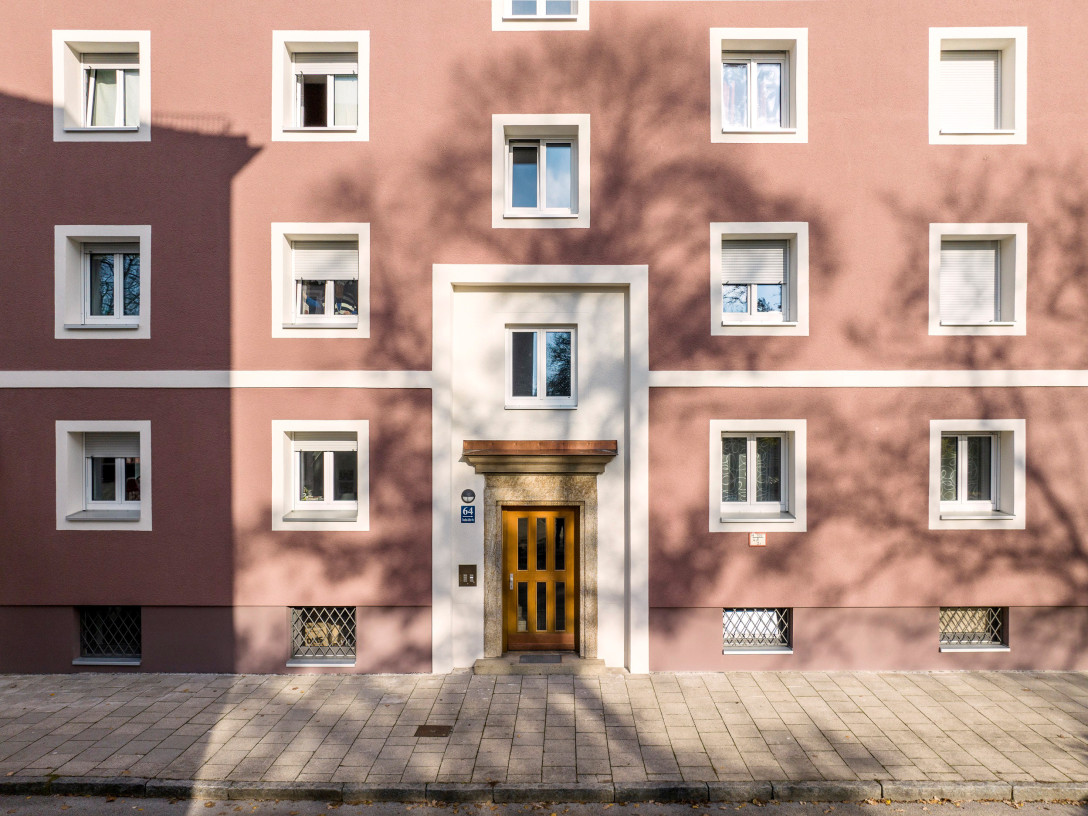 Blick auf die Fassade des Hauses. Die Fenster sind weiß umrahmt, das Haus ist auberginenfarben getsrichen.